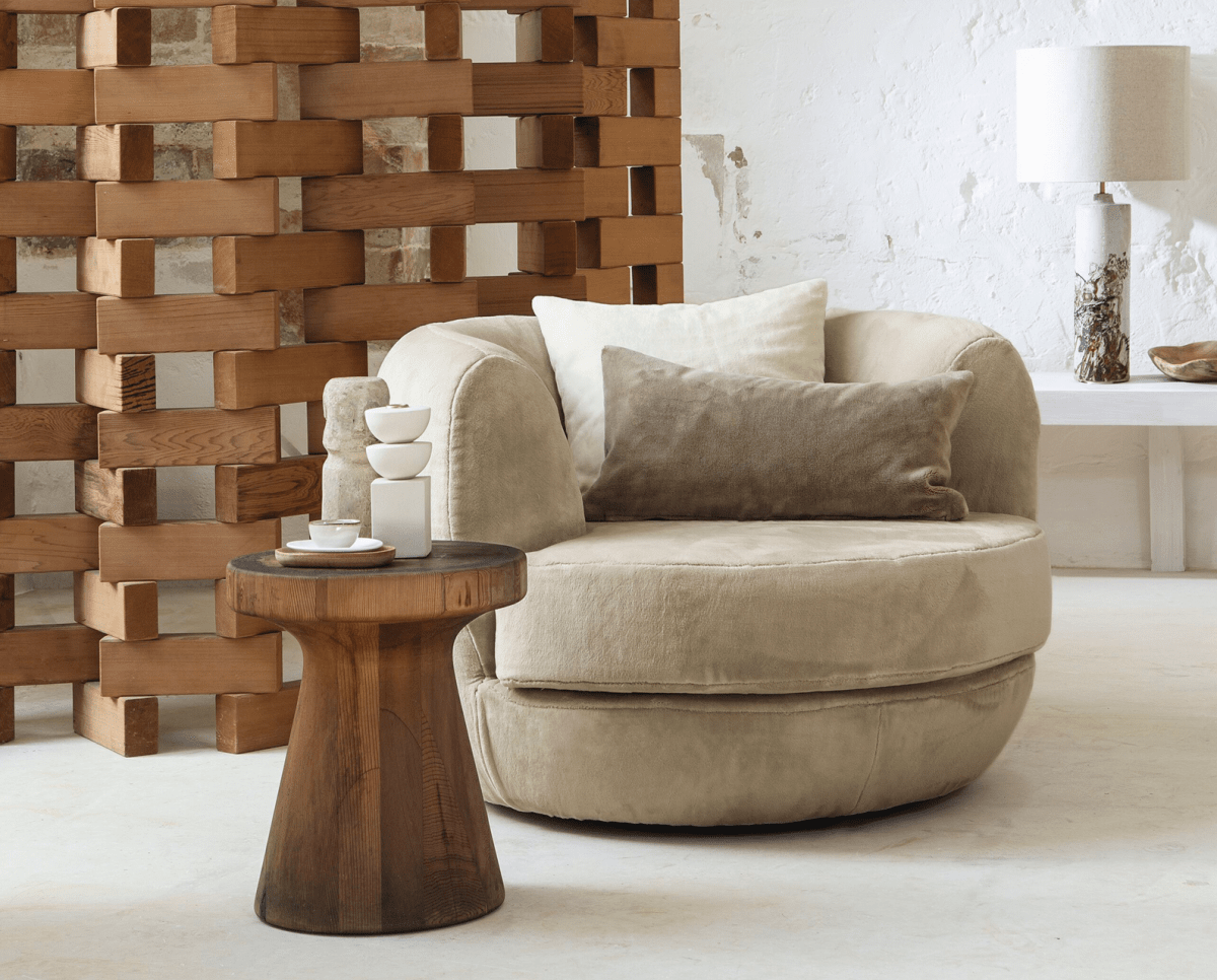 Runder Sessel in Beige vor verspielter Holzwand